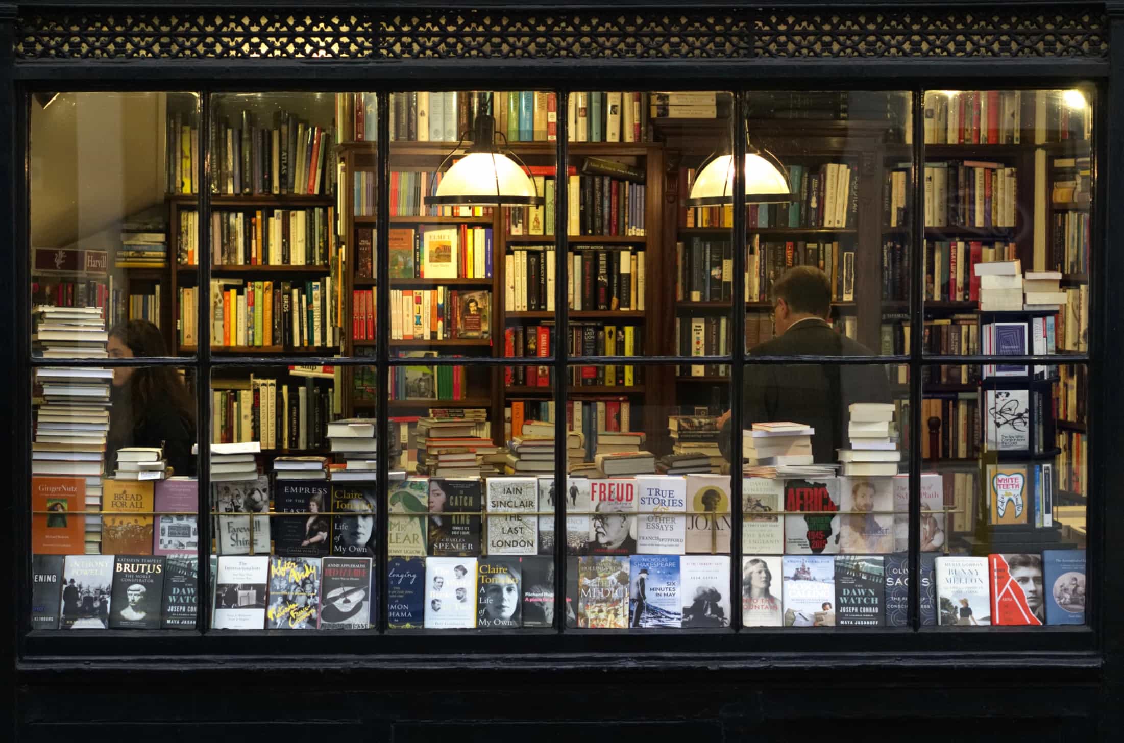 The image of a book shop window from the outside. The window is full of books.