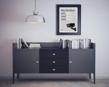 Humorous 1984 print in black frame on wall, with black sideboard and books below. From Bookish Prints collection by StrangeBooks UK