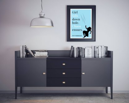 Humorous Alice in Wonderland print in black frame on wall, with black sideboard and books below. From Bookish Prints collection by StrangeBooks UK
