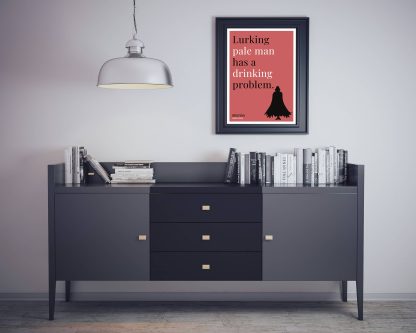 Humorous Dracula print in black frame on wall, with black sideboard and books below. From Bookish Prints collection by StrangeBooks UK