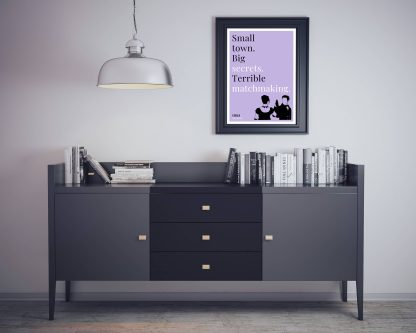 Humorous Emma print in black frame on wall, with black sideboard and books below. From Bookish Prints collection by StrangeBooks UK