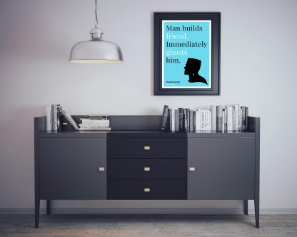 Humorous Frankenstein print in black frame on wall, with black sideboard and books below. From Bookish Prints collection by StrangeBooks UK