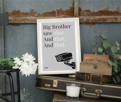 Humorous 1984 print in white wooden frame, perched on a violin case next to some books. From Bookish Prints collection by StrangeBooks UK