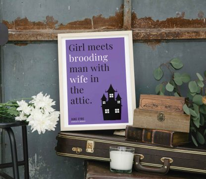 Humorous Jane Eyre print in white wooden frame, perched on a violin case next to some books. From Bookish Prints collection by StrangeBooks UK