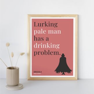 Humorous Dracula print in wooden frame, leaning against a plain wall. Small beige decoration nearby. From Bookish Prints collection by StrangeBooks UK