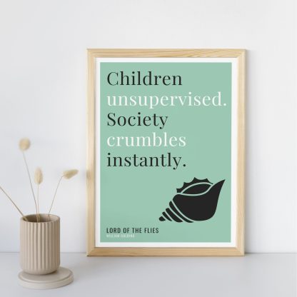 Humorous Lord of the Flies print in wooden frame, leaning against a plain wall. Small beige decoration nearby. From Bookish Prints collection by StrangeBooks UK