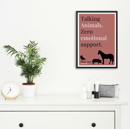 Humorous Animal Farm print in black frame on wall, with white chest of drawers and plants and candles below. From Bookish Prints collection by StrangeBooks UK