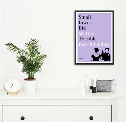 Humorous Emma print in black frame on wall, with white chest of drawers and plants and candles below. From Bookish Prints collection by StrangeBooks UK