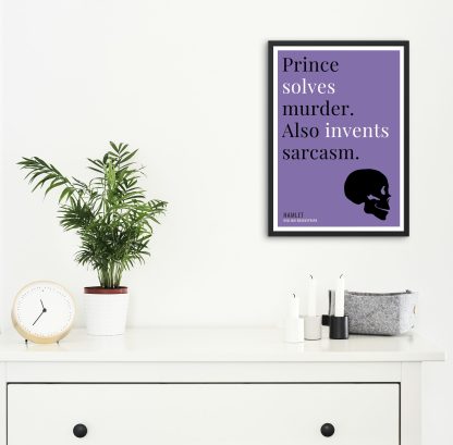 Humorous Hamlet print in black frame on wall, with white chest of drawers and plants and candles below. From Bookish Prints collection by StrangeBooks UK