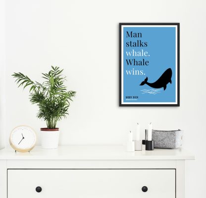 Humorous Moby Dick print in black frame on wall, with white chest of drawers and plants and candles below. From Bookish Prints collection by StrangeBooks UK