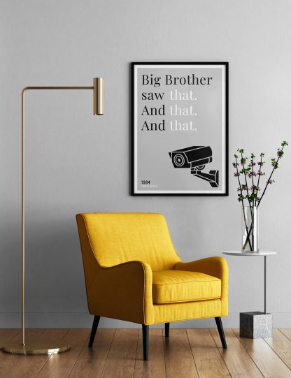 Humorous 1984 print in black frame on wall, with a yellow armchair in front next to a tall angular lamp and plant on a table. From Bookish Prints collection by StrangeBooks UK