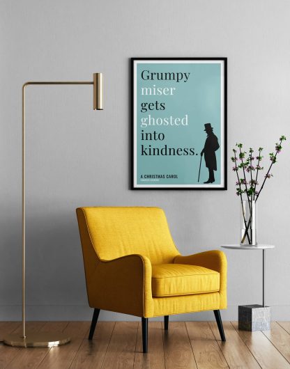 Humorous Christmas Carol print in black frame on wall, with a yellow armchair in front next to a tall angular lamp and plant on a table. From Bookish Prints collection by StrangeBooks UK