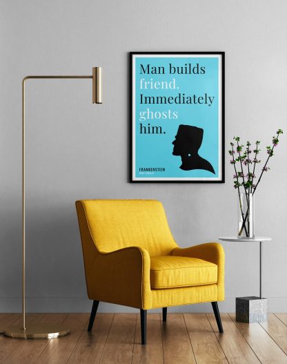 Humorous Frankenstein print in black frame on wall, with a yellow armchair in front next to a tall angular lamp and plant on a table. From Bookish Prints collection by StrangeBooks UK