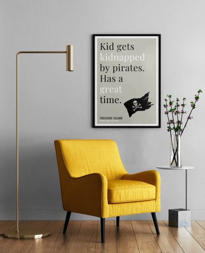 Humorous Treasure Island print in black frame on wall, with a yellow armchair in front next to a tall angular lamp and plant on a table. From Bookish Prints collection by StrangeBooks UK