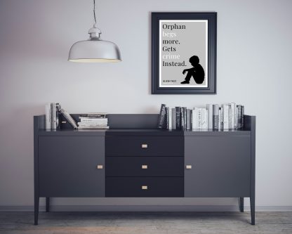 Humorous Oliver Twist print in black frame on wall, with black sideboard and books below. From Bookish Prints collection by StrangeBooks UK