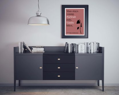 Humorous Picture of Dorian Gray print in black frame on wall, with black sideboard and books below. From Bookish Prints collection by StrangeBooks UK