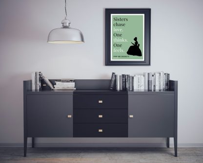 Humorous Sense and Sensibility print in black frame on wall, with black sideboard and books below. From Bookish Prints collection by StrangeBooks UK
