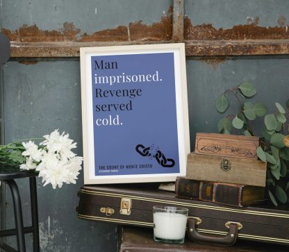 Humorous The Count of Monte Cristo print in white wooden frame, perched on a violin case next to some books. From Bookish Prints collection by StrangeBooks UK