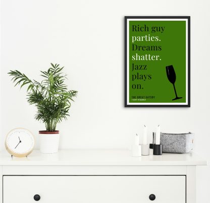 Humorous The Great Gatsby print in black frame on wall, with white chest of drawers and plants and candles below. From Bookish Prints collection by StrangeBooks UK