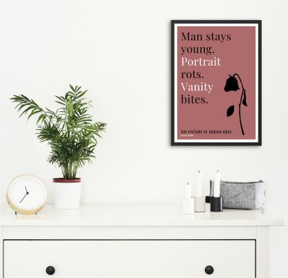 Humorous Picture of Dorian Gray print in black frame on wall, with white chest of drawers and plants and candles below. From Bookish Prints collection by StrangeBooks UK