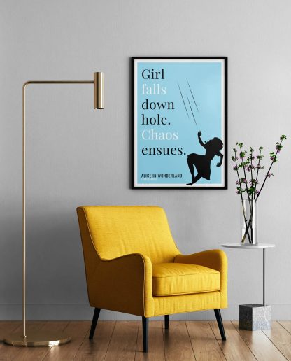 Humorous Alice in Wonderland print in black frame on wall, with a yellow armchair in front next to a tall angular lamp and plant on a table. From Bookish Prints collection by StrangeBooks UK