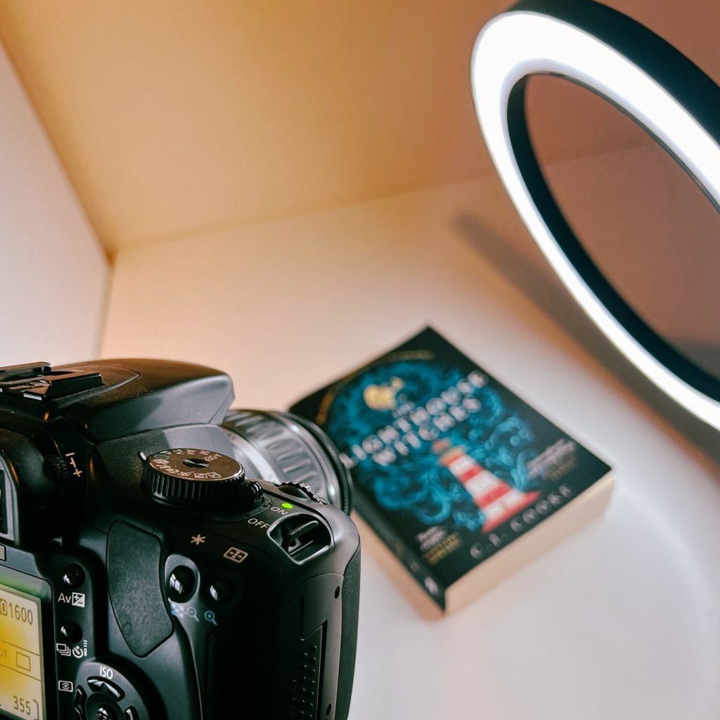 An image showing how books are photographed at StrangeBooks. There is a main camera pointing at a paperback book. A ring light is also shown.