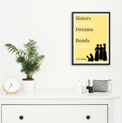 Humorous Little Women print in black frame on wall, with white chest of drawers and plants and candles below. From Bookish Prints collection by StrangeBooks UK